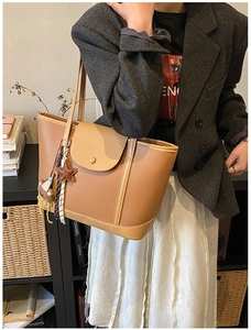 Detail of lychee textured leather tote bag in camel with star and bear charms
