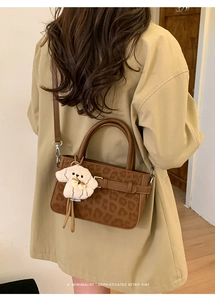 Détail du sac à main à motif léopard avec boucle décorative et breloque chiot