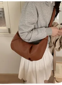 Model wearing dark brown oversized slouchy leather hobo bag with pleated dumpling shape