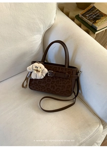 Détail du sac à main léopard avec sangles en cuir et un charmant pendentif chiot blanc