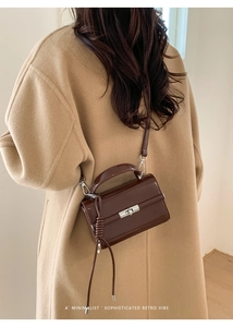 Detail of a dark brown glossy leather square handbag with silver metal swivel lock