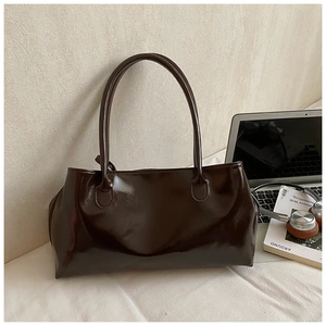 Detail view of large dark brown polished leather tote bag with long shoulder straps