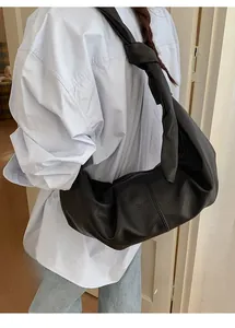 Close-up of black leather hobo bag with signature knot detail on the shoulder strap