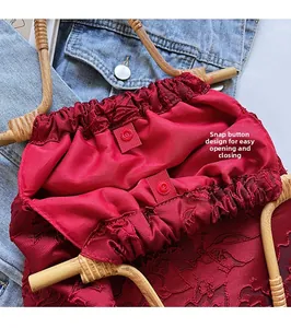 Close-up of red jacquard handbag showing snap button closure and wooden handle detail