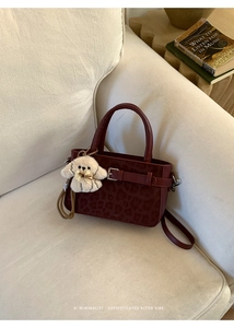 Sac à main bordeaux à motif léopard sur canapé beige avec un adorable charme de chiot