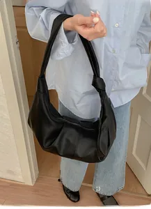 Close-up of black leather hobo bag featuring unique knotted strap detail and pebble texture