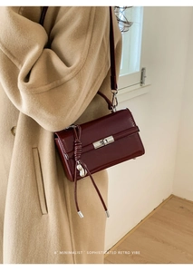Close-up of retro burgundy shoulder bag with silver twist lock and woven strap detail