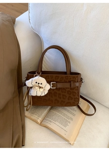 Détail d'un sac à main léopard marron avec breloque chien peluche sur livres rétro