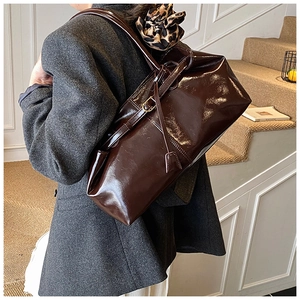 Detail of dark brown oil wax leather tote bag with leopard print scarf on the shoulder strap