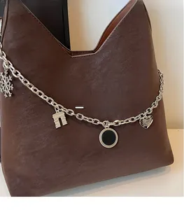 Close-up of deep brown leather tote with vintage texture and silver charms detail