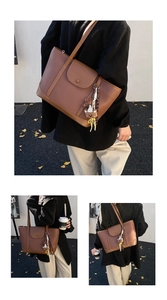 Detail of caramel brown leather tote bag with cute bear charm and decorative floral scarf