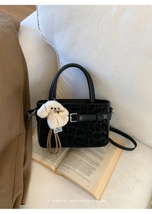 Détail d'un sac à main noir à motif léopard avec un pendentif chien en peluche