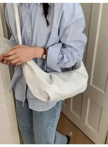 Detail of white pleated crescent bag in textured leather worn with casual denim outfit