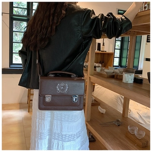 Detail of vintage brown leather satchel with silver buckle closures and metal crest