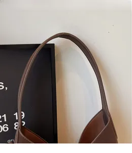 Close-up of smooth long leather shoulder strap on a dark brown bucket bag details