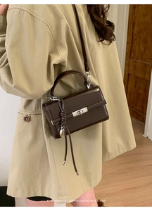Detailed close-up of retro brown leather square bag featuring a silver twist lock and tassel