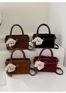 Détail de quatre mini sacs à main noir et léopard avec des breloques en peluche pour chien