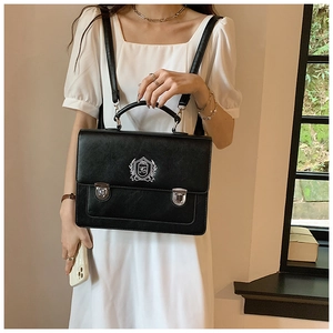 Detail of black vintage satchel bag featuring shield crest print and silver metal buckles