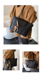 Macro view of black litchi grain leather tote bag featuring a decorative front pocket