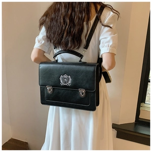 Detail of British collegiate style black bag with embroidered crest and metal buckles