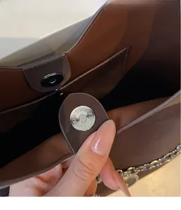 Macro shot of silver magnetic clasp and interior pocket on a brown leather tote bag