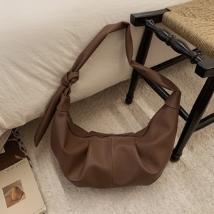 Detail of the knotted shoulder strap on a brown soft leather crescent dumpling bag