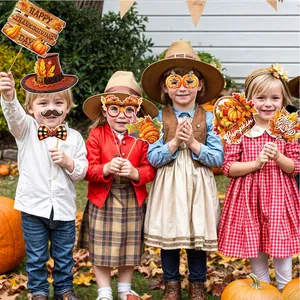 Group of happy children using turkey and pumpkin props for Thanksgiving photo booth fun