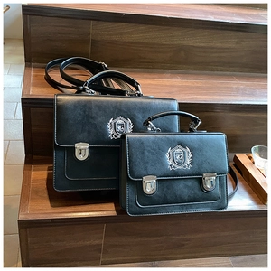 Detail of two black vintage satchels with metal buckles and embroidered crest logo