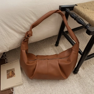 Close-up of caramel leather dumpling bag showing soft pleats and pebbled texture detail