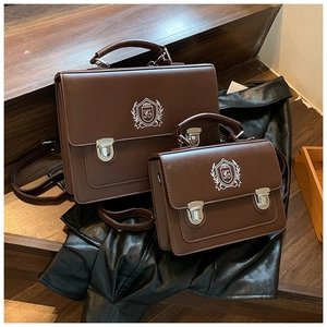 Detail of vintage brown satchel bags with school crest and silver metal buckles