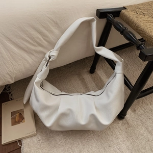 Detailed view of white hobo bag with litchi grain leather and knotted strap detail
