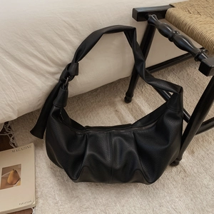 Detail of black lychee texture crescent bag with knotted strap and metal zipper