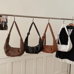 Detail of four retro soft leather croissant bags with knotted straps hanging in a row