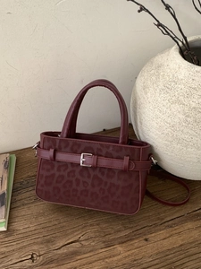 Sac à main chic bordeaux avec flocage léopard sur une surface en bois rustique