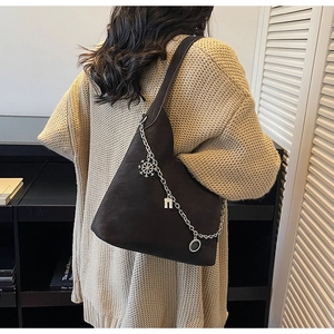 Detail of dark brown matte bucket bag with silver chain and metal charms decoration