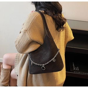 Deep brown suede tote bag with decorative metal chain charms and heart pendants