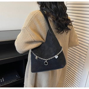 Detail view of black suede hobo bag with silver chain and heart-shaped charms