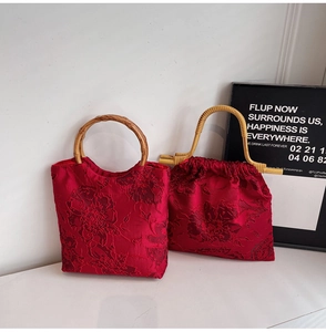 Detail of red embroidered satin handbag set with natural bamboo handles and floral patterns