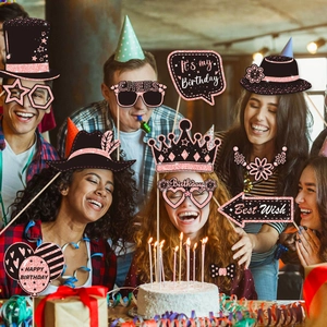 Group of friends using black and pink birthday photo booth props at a festive party