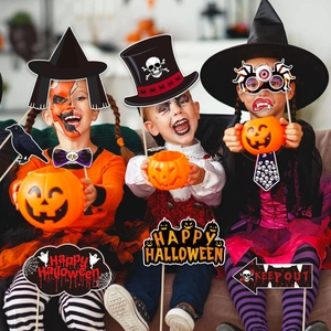 Tres niños jugando con accesorios de fotos para Halloween como calabazas y sombreros