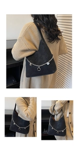 Detailed macro of black suede tote bag with silver chain charms and contrast brown lining