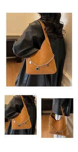 Detail of caramel hobo bag featuring decorative silver chain with heart charms