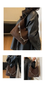 Detail of dark brown suede bucket bag with decorative silver chain and charms
