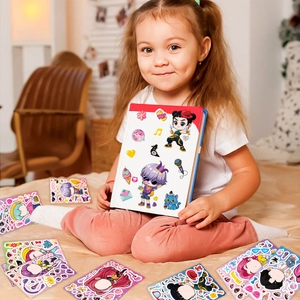 Girl showing colorful cartoon party stickers set on a notebook in a cozy bedroom