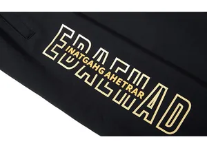 Detail of artistic gold lettering and silk-screen printing on black athletic shorts