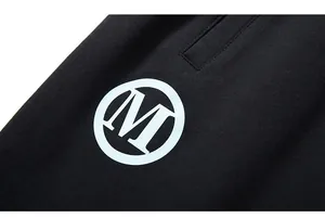 Close-up of white circle M logo print on black cotton streetwear sports shorts