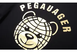 Makroaufnahme von goldenem Bärendruck und PEGAUAGER-Text auf schwarzem Baumwoll-T-Shirt