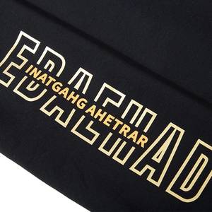 Black loose sports shorts with metallic gold graphic print and textured knit fabric