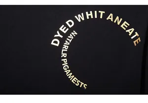 Macro detail of golden lettering print on black cotton fabric of an oversized T-shirt