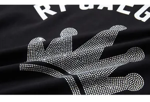 Detailed close-up of shiny silver rhinestone crown and white letters on a black T-shirt